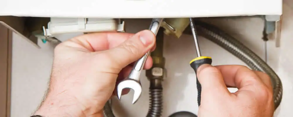 Boiler repair technician tightening pipe fittings and connections in Des Moines, IA
