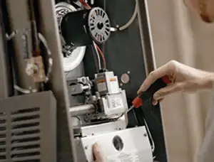 Furnace repair technician inspecting internal components and wiring in Des Moines, IA