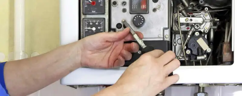 Heating repair technician adjusting boiler controls and components in Des Moines, IA