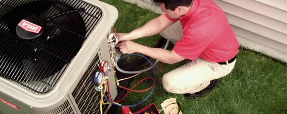HVAC technician servicing an outdoor air conditioner unit in Des Moines, IA