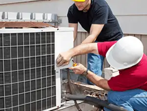 HVAC technicians repairing an outdoor AC unit on a rooftop in Des Moines, IA