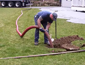 Septic pumping technician servicing a residential septic tank with a vacuum hose in Des Moines, IA