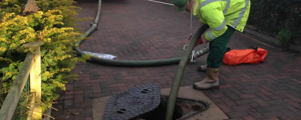 Septic tank cleaning technician servicing a septic tank with a vacuum hose in Des Moines, IA