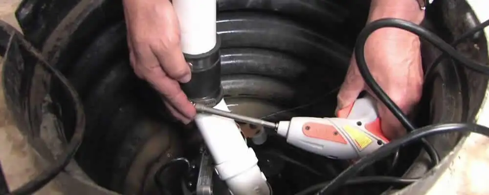 Sump pump installation technician connecting PVC discharge piping in Des Moines, IA