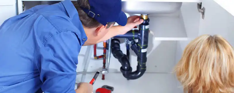 Plumber repairing under-sink drain pipes and fittings in Des Moines, IA